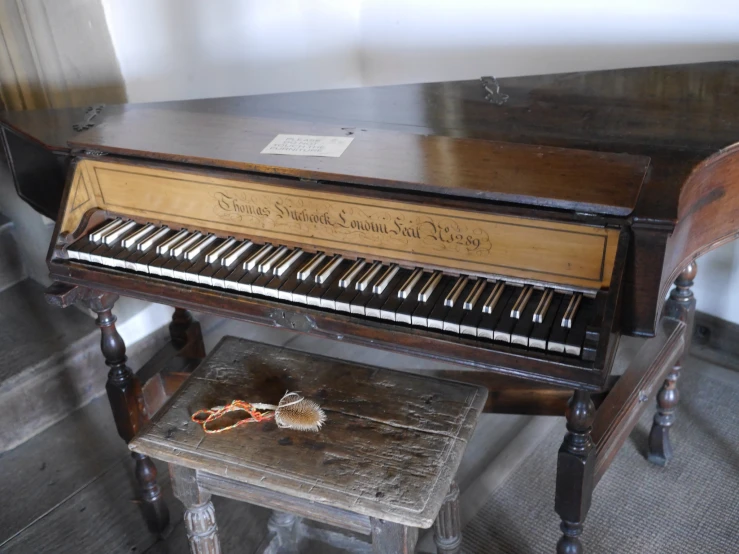 a very old piano with a stool in the middle