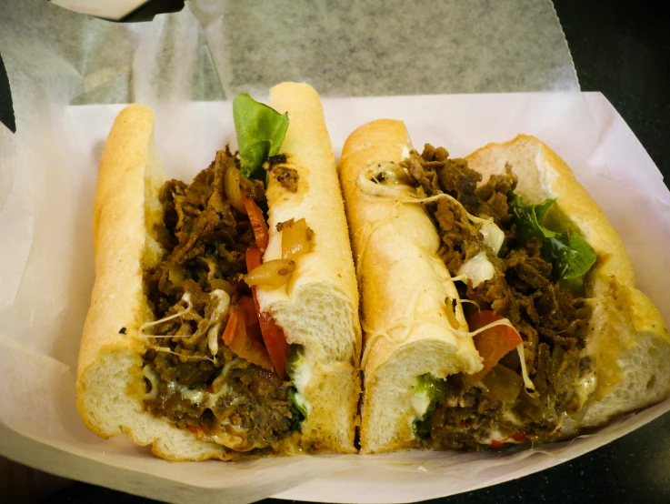 two sandwiches with meat and greens in a basket