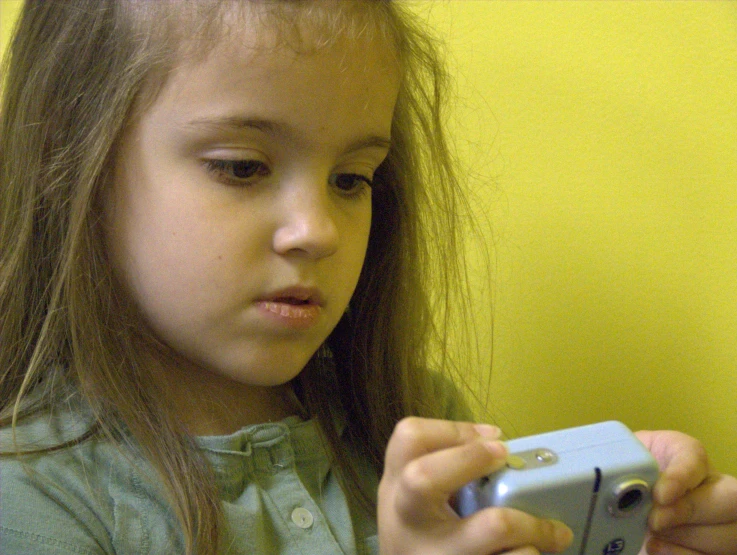 a little girl looking at a camera, she is holding her phone
