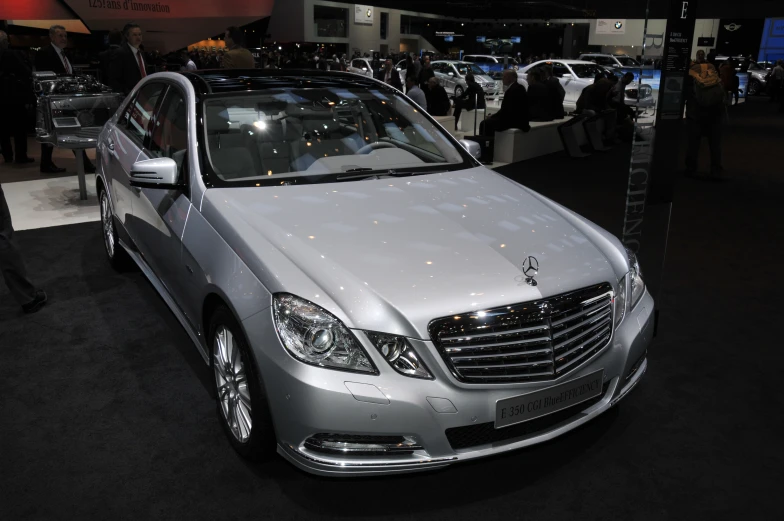 a grey car is parked on a black carpet in front of some people