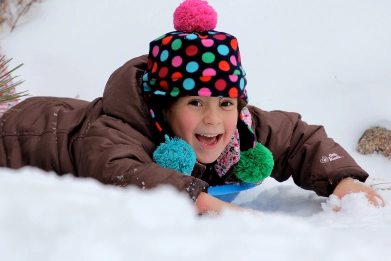 little girl is smiling while laying in the snow