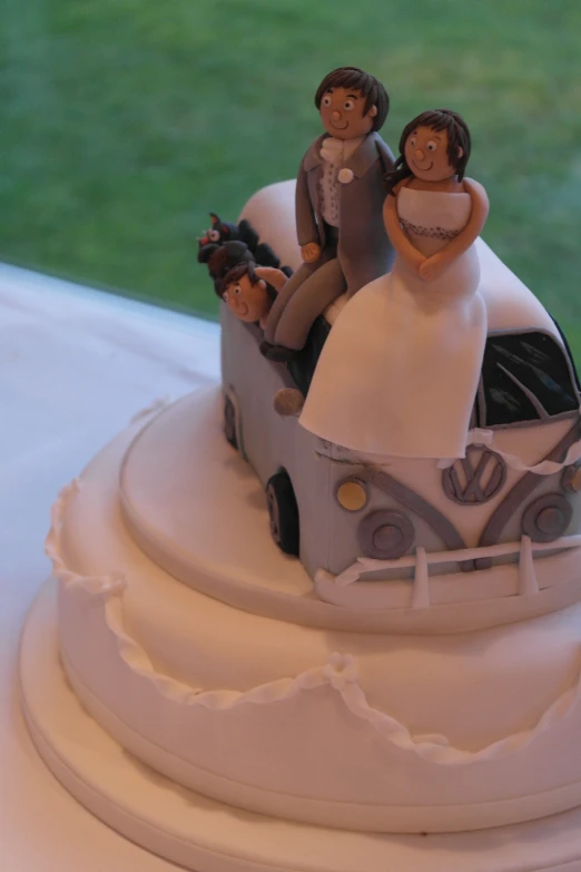 a couple riding on top of a car on a cake