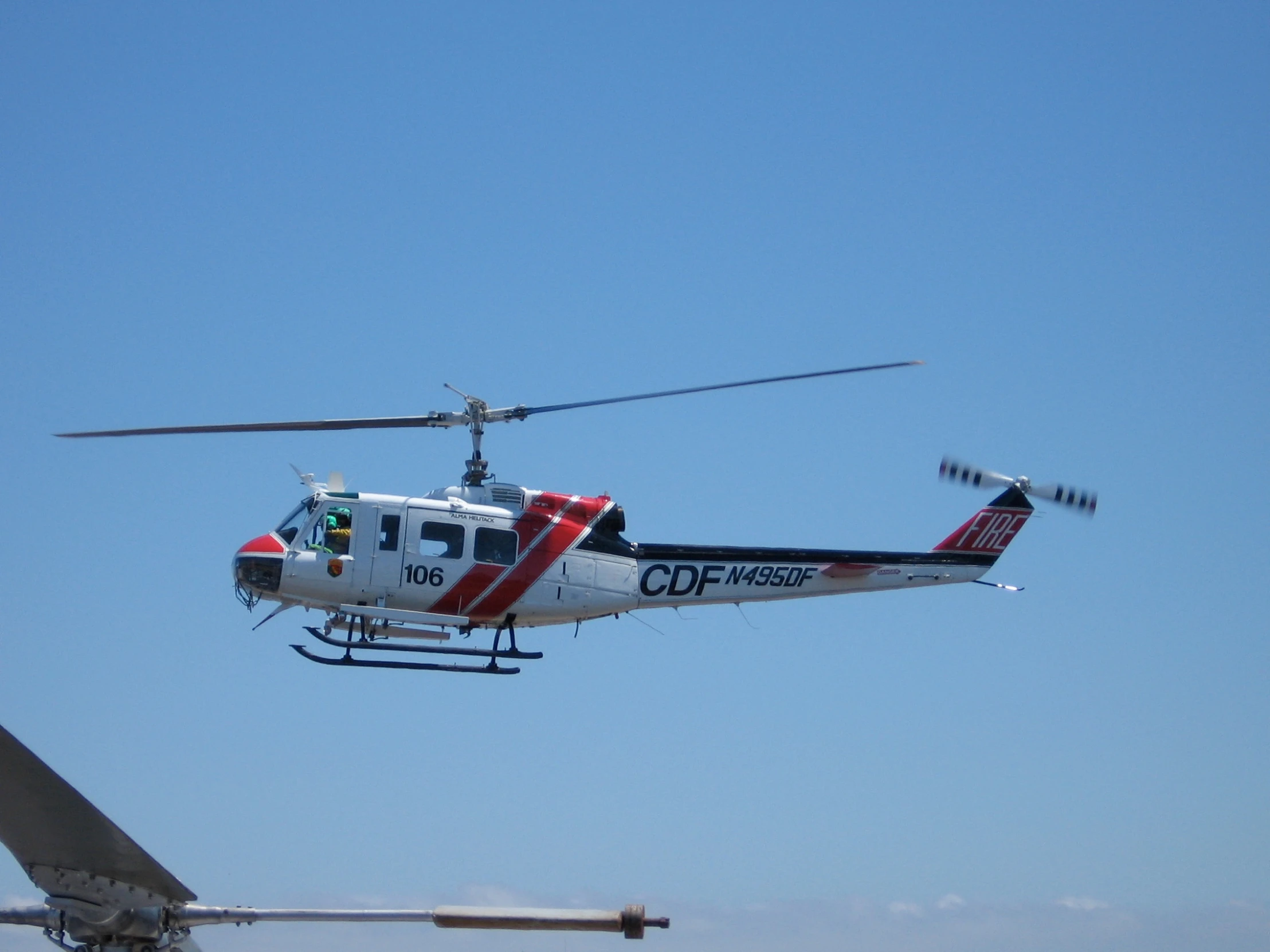 a helicopter flying through a blue sky near a jet