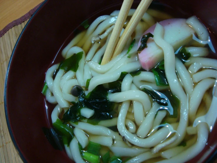 a bowl full of pasta and vegetables with chopsticks