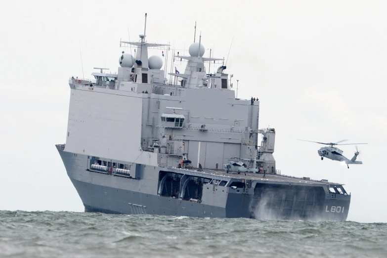 a helicopter landing on a ship near a large boat