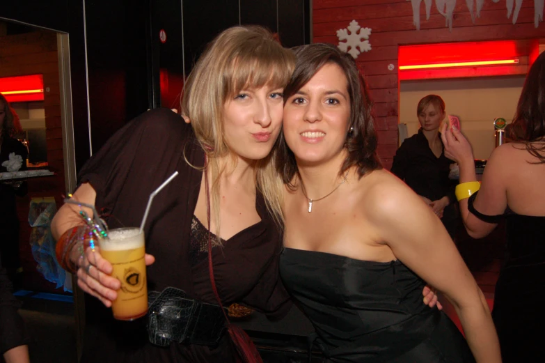 two young women are posing for the camera with drinks