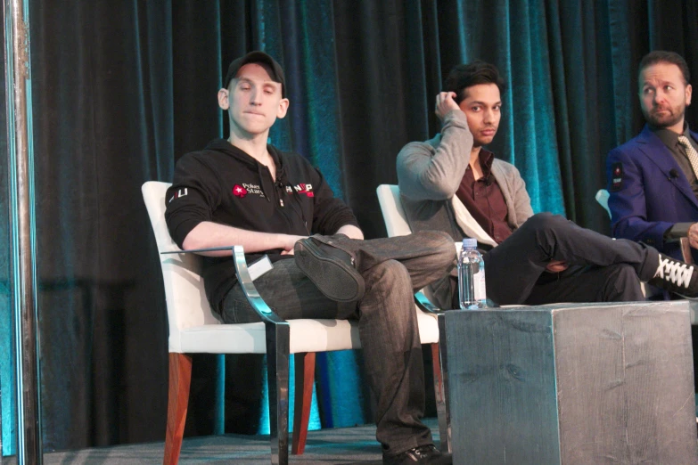 two men sitting down on chairs with microphones