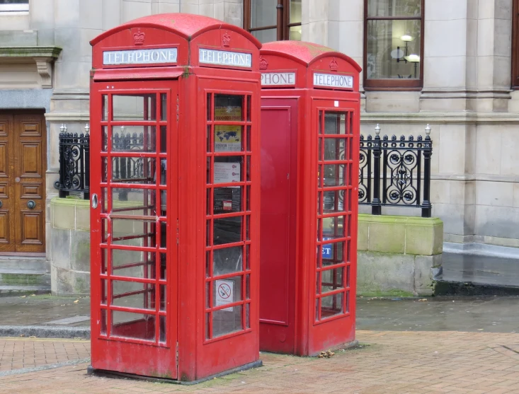 two red telephone booths are standing side by side