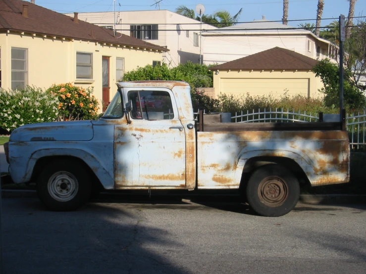 an old rusty pick up truck is parked next to a house