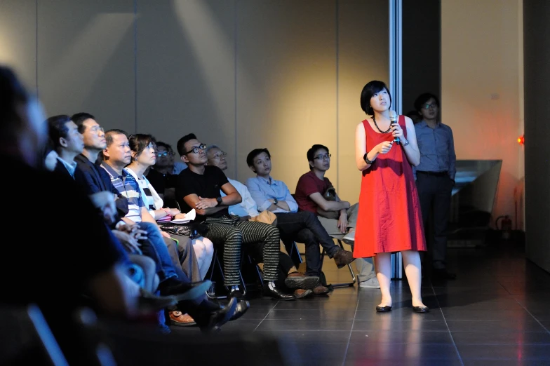 a woman in an orange dress speaking to an audience