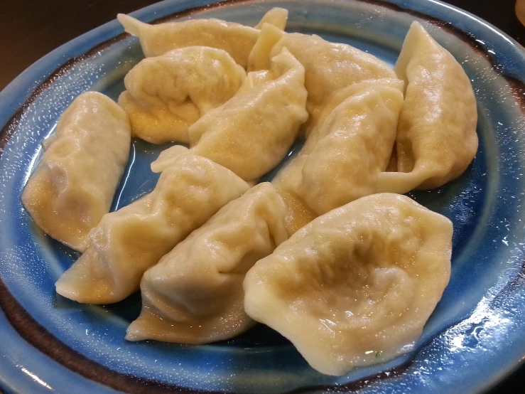 some dumplings are in a blue plate on a wooden table