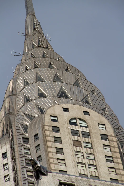 a tower made of triangular stone sits on a gray sky