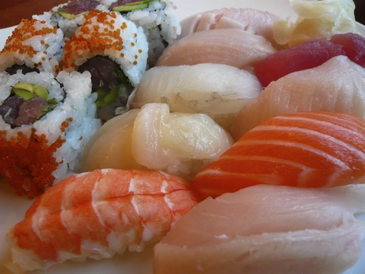 a white plate with assorted sushi and chop sticks