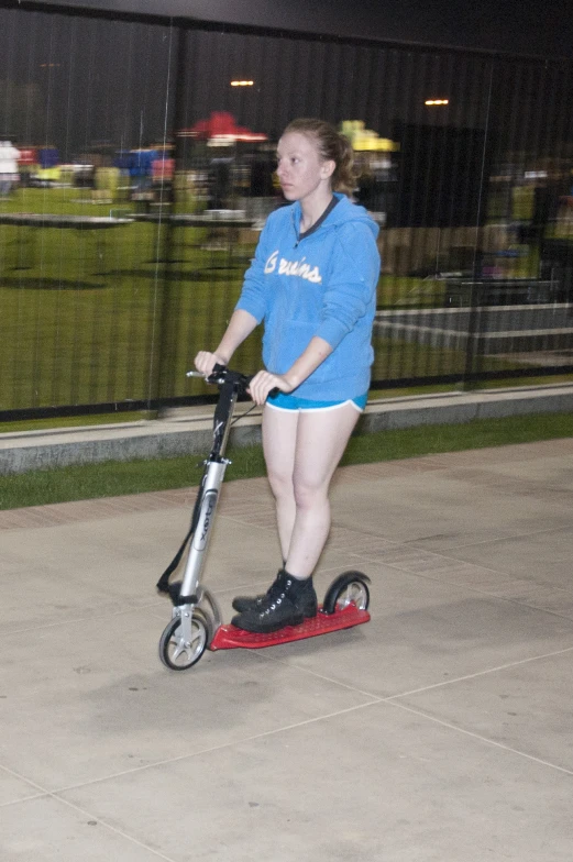 the girl is riding a scooter in her shorts