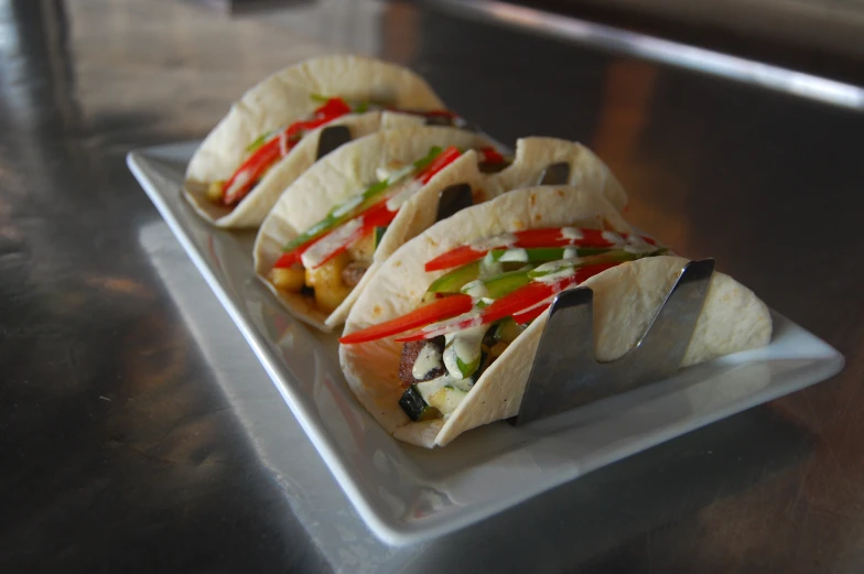 four tacos that are on top of a white plate