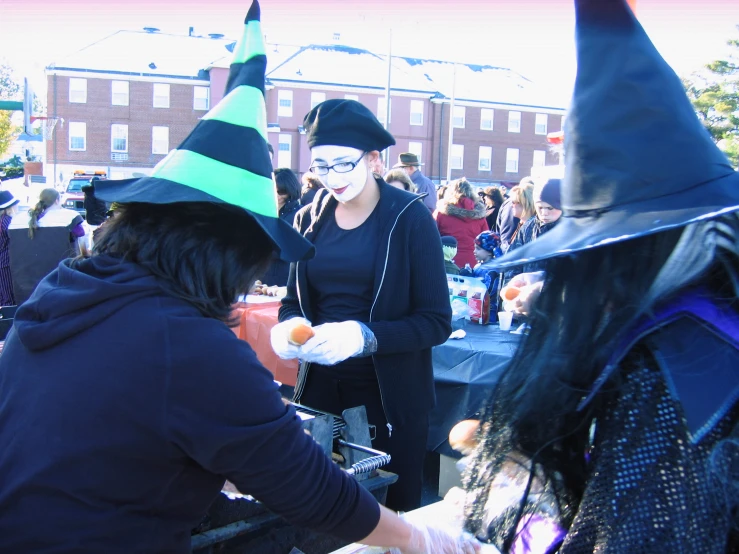 three young women in witches hats at a halloween parade