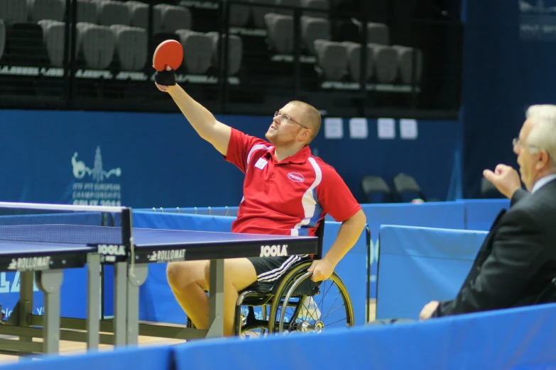 a tennis player in a wheelchair is holding his ping pong racket