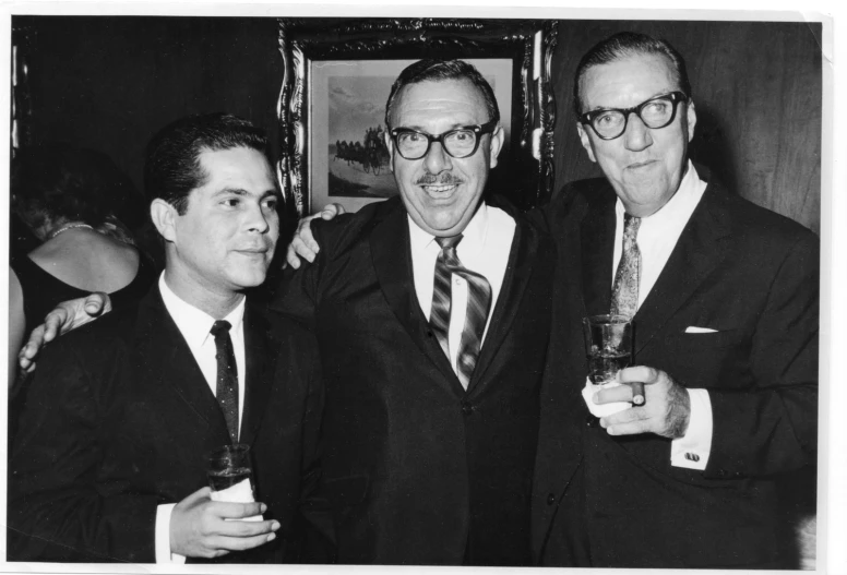 three men in business attire are holding a drink