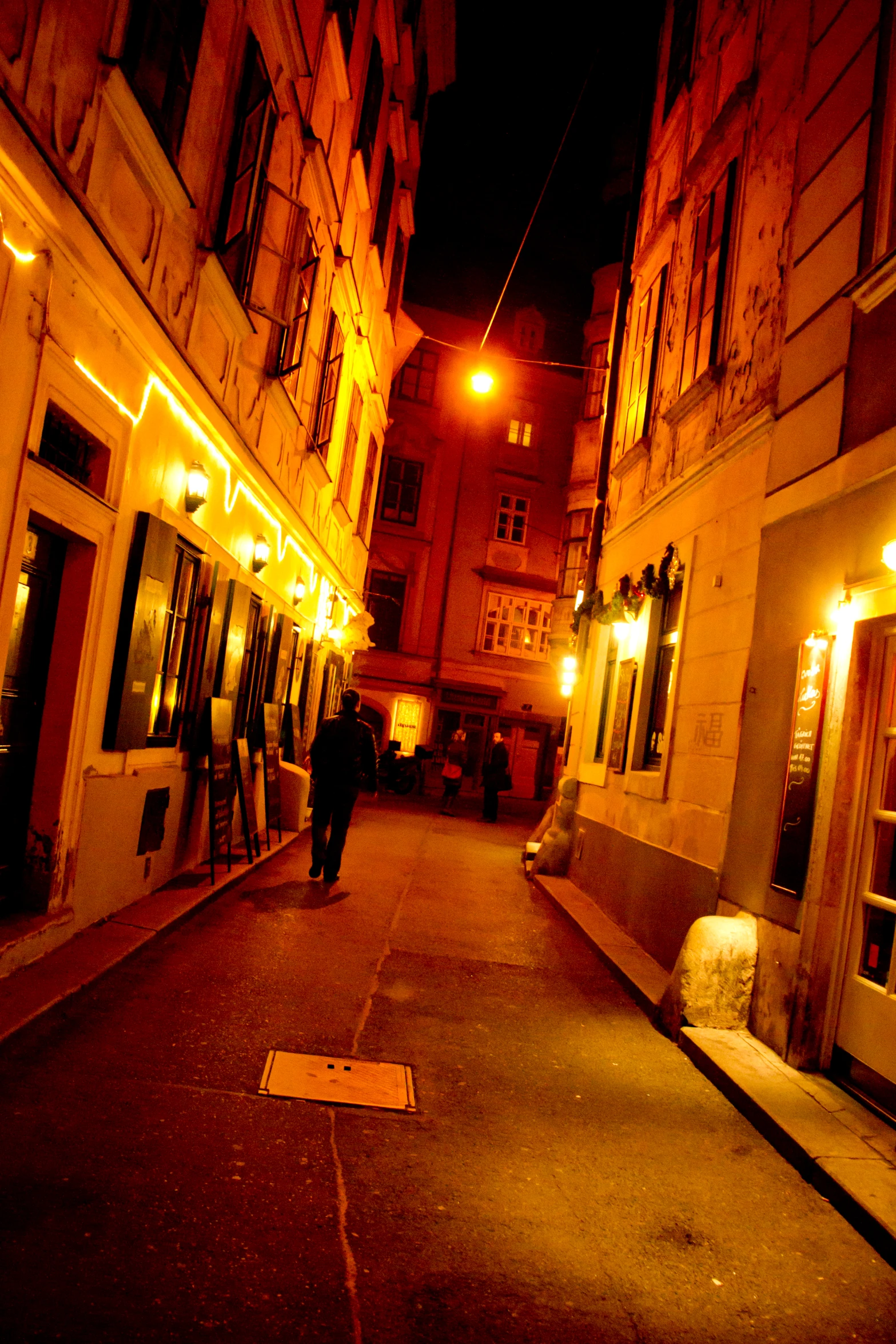 a couple of people walking down a street in the dark