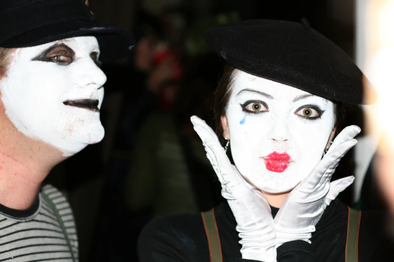 a woman in black with painted on her face and hands with white paint