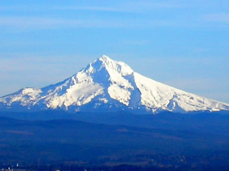 a large snow covered mountain peak towering over a town