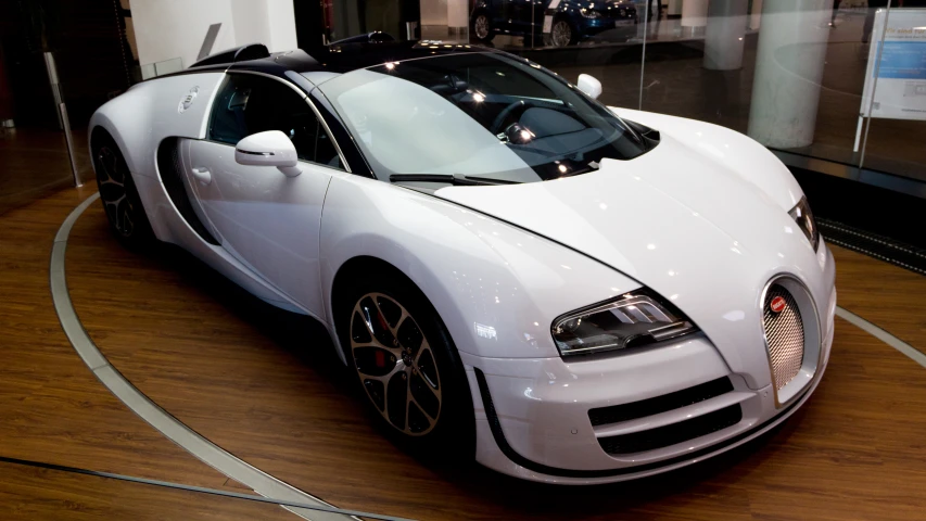 a very clean white bugatti parked in front of a glass window