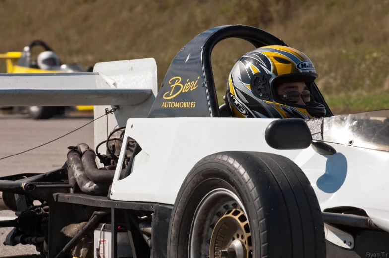 a man driving a racing car while sitting inside of a pits lane