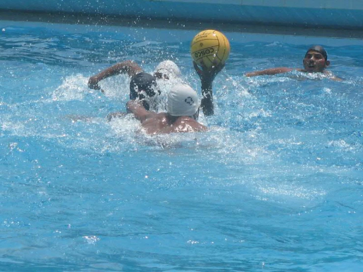 people playing volleyball in a pool while two others watch