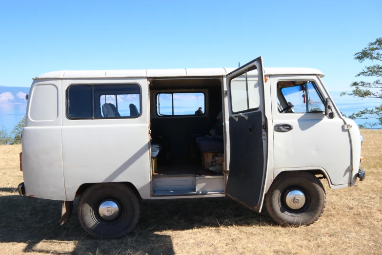 the van is parked on the grass and has it door open