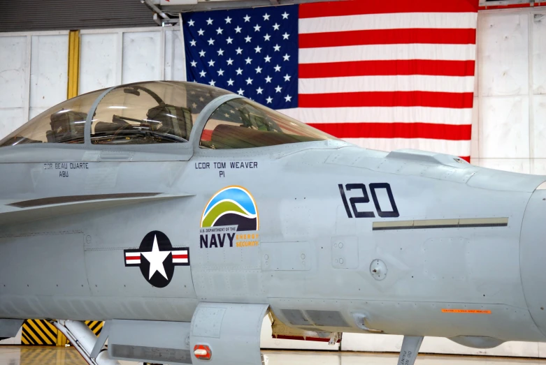 a jet fighter parked in a hanger with american flag in background