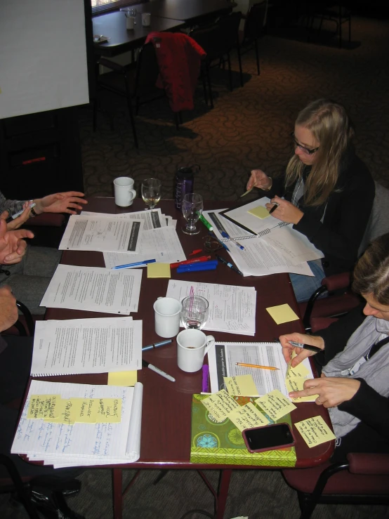 several people sitting around a table covered in paper