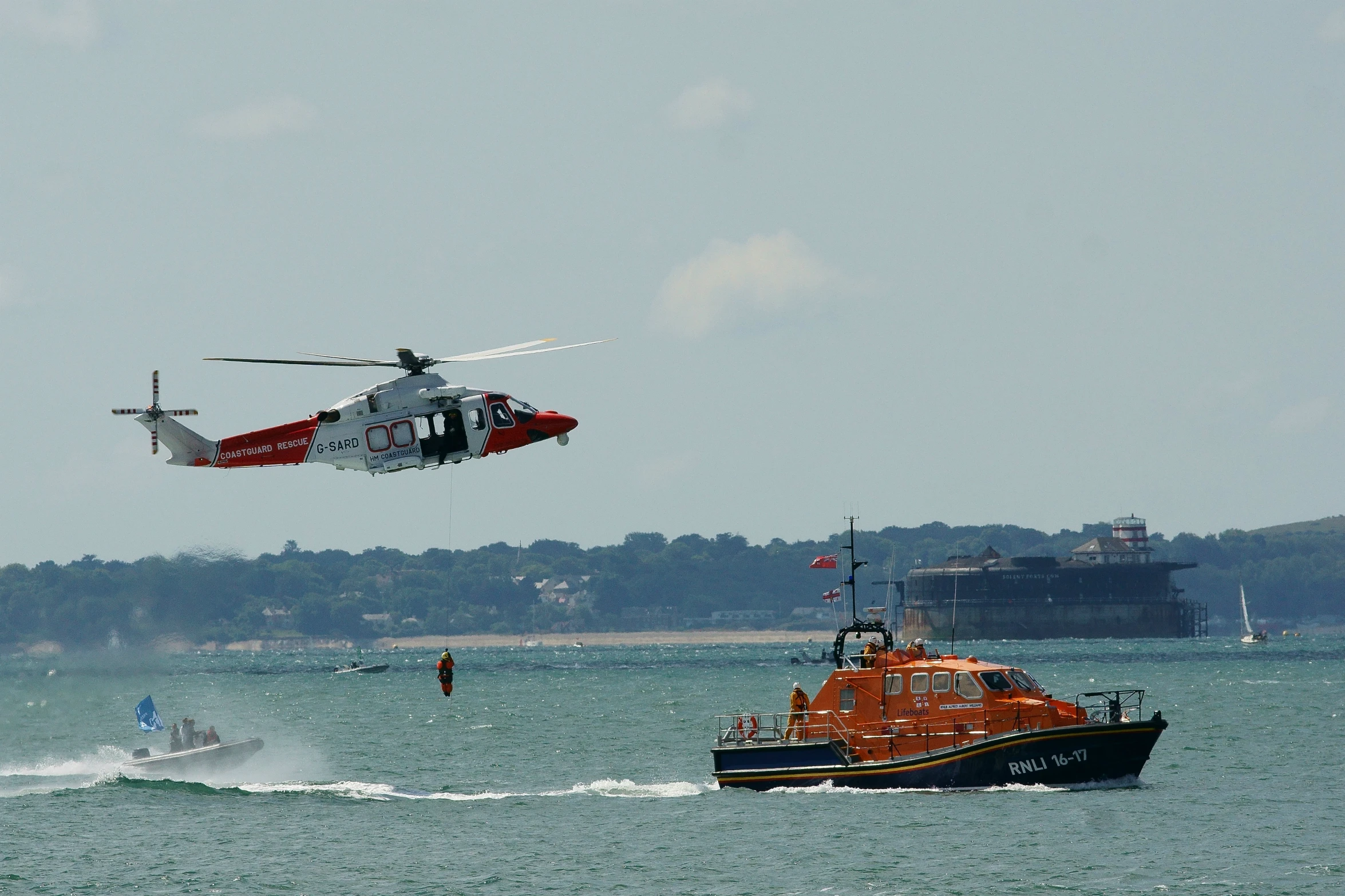 a helicopter is flying over the water by a boat