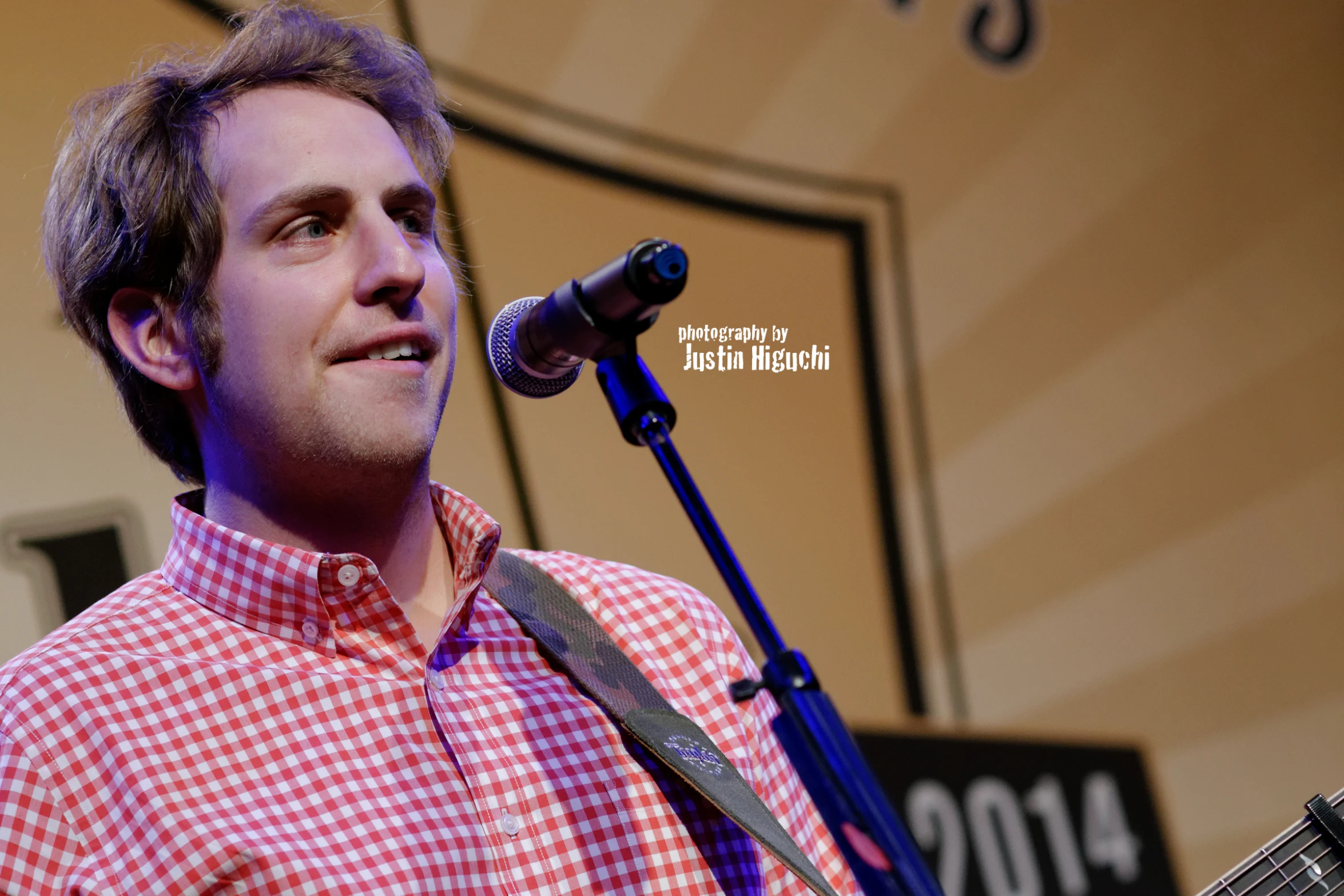 the man holds onto his tie as he talks into a microphone