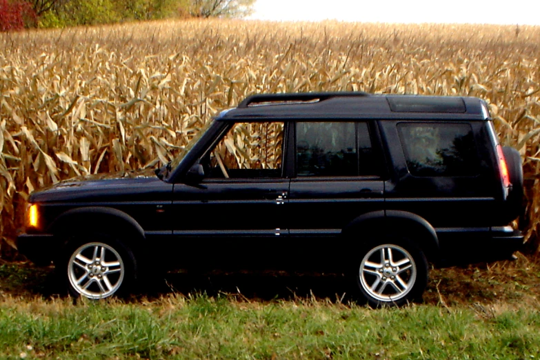 an suv parked in front of a cornfield