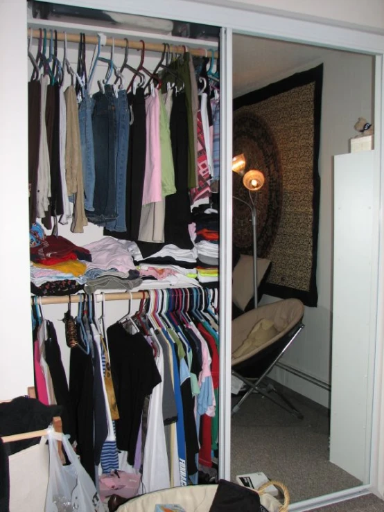 a closet with clothes and bags on hangers