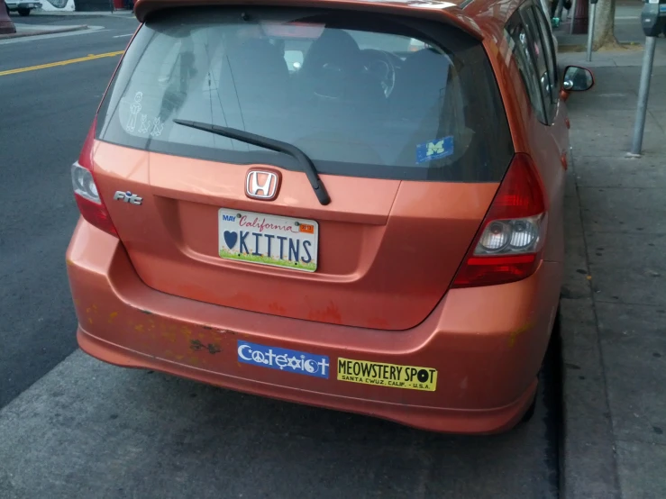 an orange honda fit is parked on the side of the road