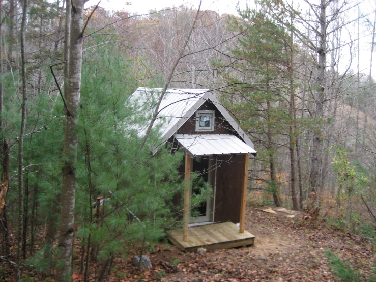 an outhouse on the side of a path in the woods