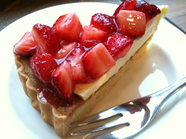 a slice of tart with strawberry topping and two forks