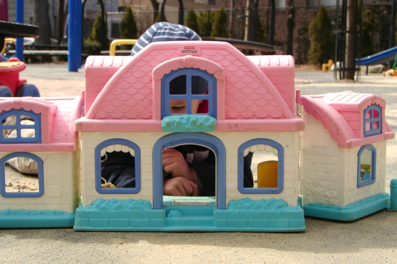 a little boy sitting in a play house with its windows opened