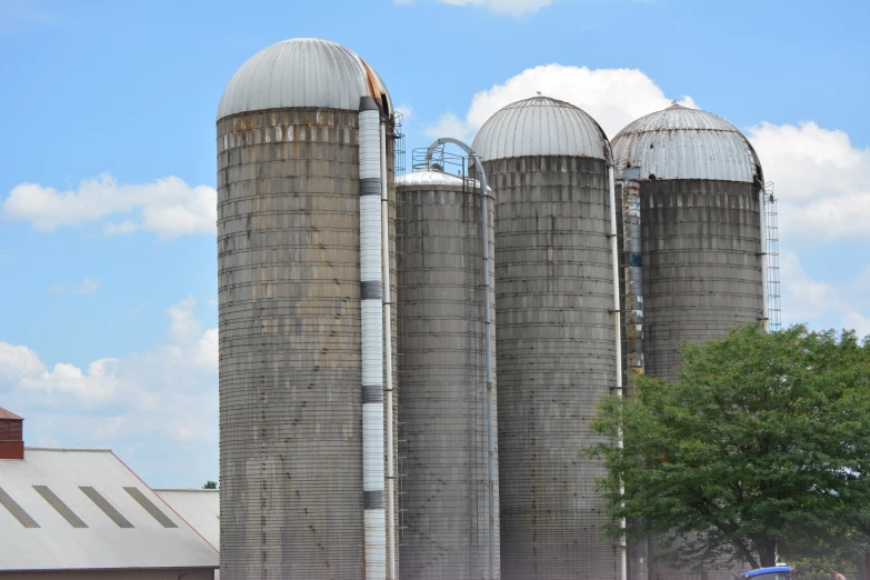 three silos with a fence around them on the side of a farm