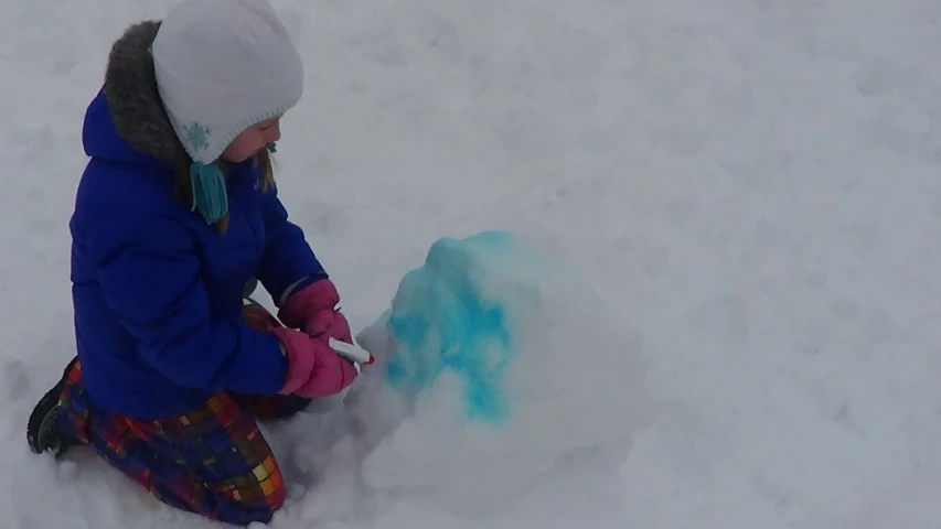 a young child plays with her snowman outside