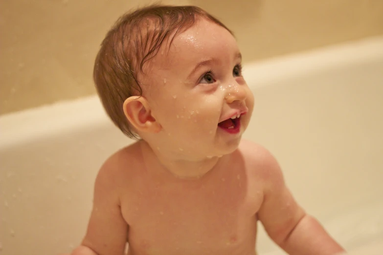a baby sitting in a bathtub and playing with some water