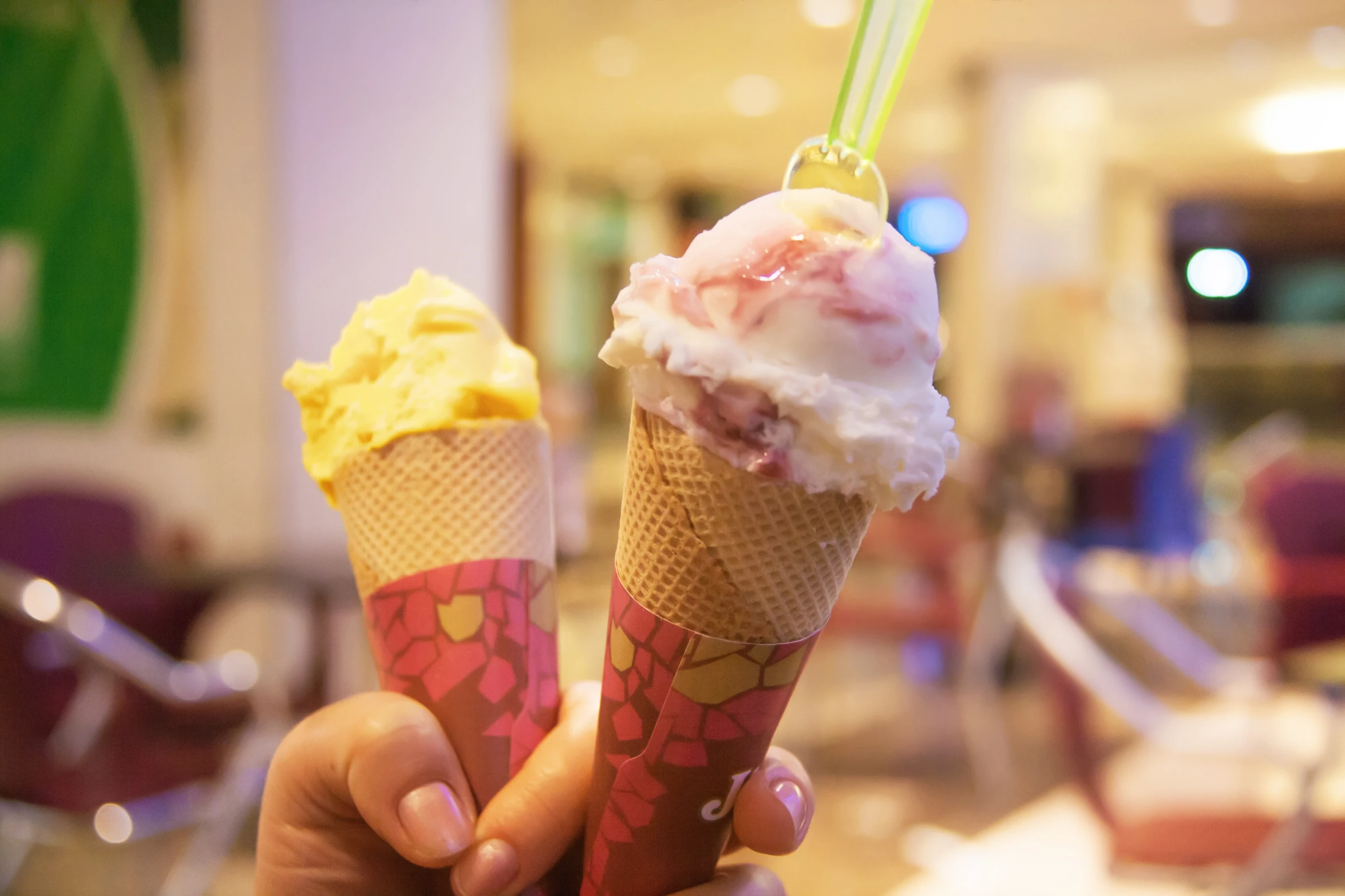 a hand holding an ice cream cone with a spoon sticking out of it