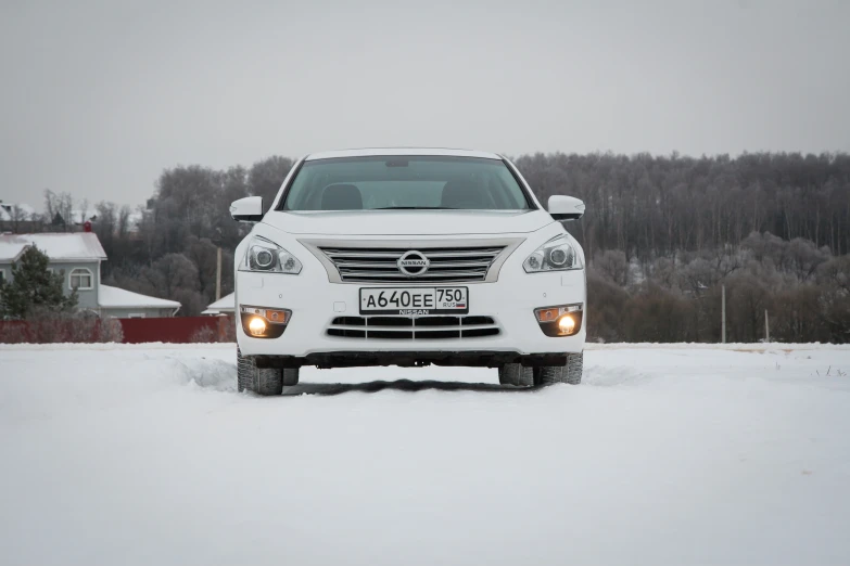 a white car with lights on parked in the snow