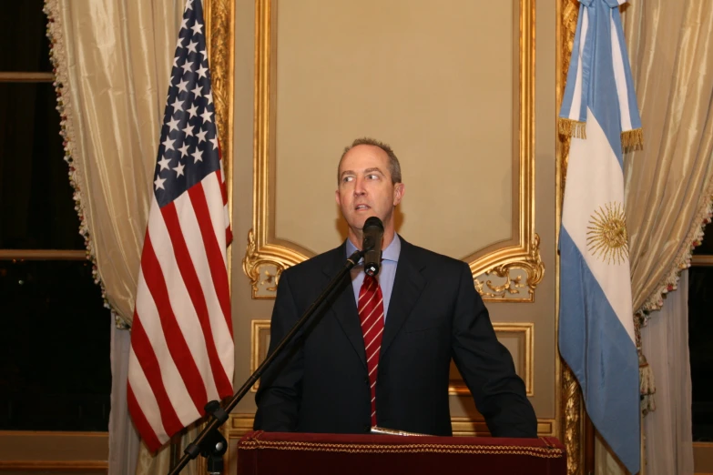 a man wearing a suit and tie in front of a podium