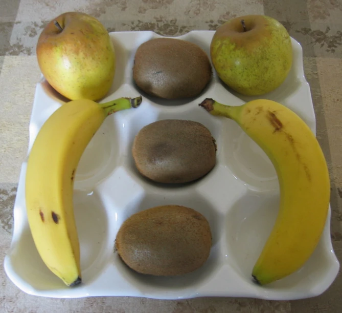a white tray with a banana, kiwis and pears