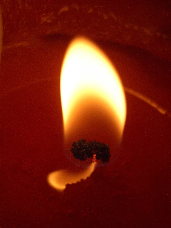 a red candle with some black stuff on the side