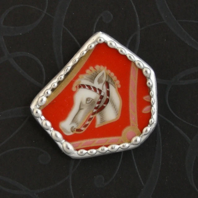 a red and white decorative brooch on black background