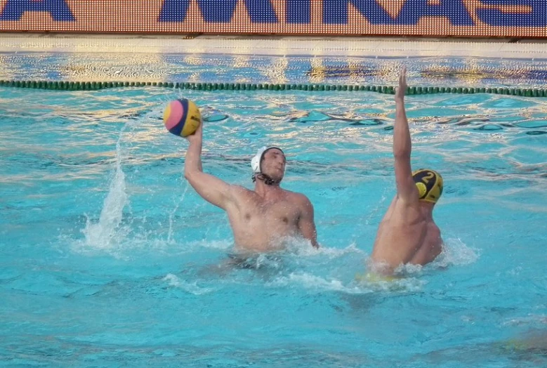 men playing water polo in a pool, with the ball just above their head