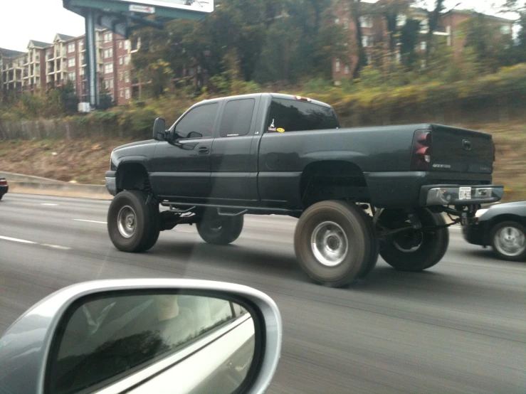 there is a large black truck driving down the road